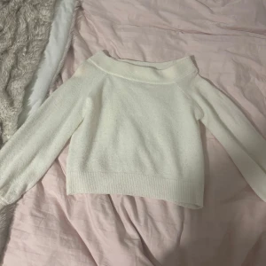 Vit offshoulder tröja - Säljer en stilren vit offshoulder tröja med långa ärmar. Perfekt för en avslappnad look. Tröjan har en mjuk och bekväm passform. (En fläck vid axeln, tror den går bort i tvätten. Tvättar varan innan jag skickar den)