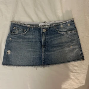 Blå mini jeanskjol  - Snygg blå jeanskjol från Pull&Bear i en kort modell. Kjolen har slitna detaljer och fransig nederkant för en trendig look. Perfekt för en avslappnad stil.