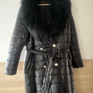 Grå kappa med bälte - Elegant grå kappa med ett brett bälte i midjan och en stor krage. Perfekt för kyliga dagar med sin stilrena design och långa ärmar.