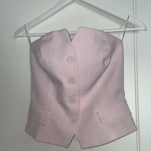 Rosa korsettopp från FB Sister - Säljer en söt rosa korsettopp från FB Sister. Toppen har knappar framtill och en volangdetalj baktill. Perfekt för att ge en feminin touch till din outfit. 💖