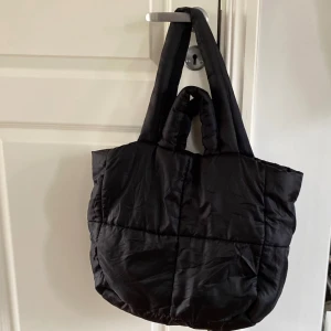 Svart quiltad shoppingväska - Svart vadderad shoppingväska med handtag. 