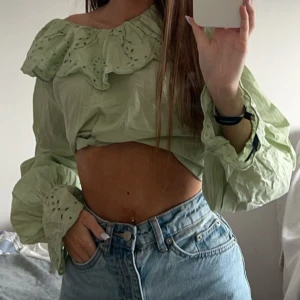 Grön blus med volangdetaljer - Säljer en söt grön blus med volangdetaljer och broderade mönster. Blusen har långa ärmar och en luftig passform, perfekt för vår och sommar. 
