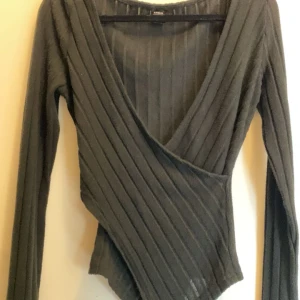 Svart ribbad omlottopp - Säljer en stilren svart ribbad omlottopp med lång ärm och v-ringning. Perfekt för en elegant look. Passar bra till både jeans och kjol. Den är i nyskick från Shein i storlek XS