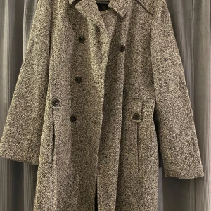 Grå kappa med knappar - Grå kappa med trippelknäppning och klassisk krage. 