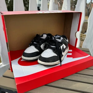 Nike Dunk i svart och vitt stl 33 - Snygga Nike Dunk sneakers i klassisk svart och vit färgkombination. Skorna har en låg profil med snörning och en bekväm passform. Perfekta för en stilren look. 
