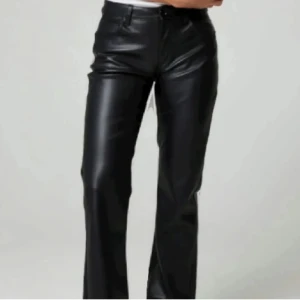 Svarta skinnbyxor - Snygga svarta skinnbyxor med hög midja och bootcut-stil. Perfekta för en trendig look. Byxorna har en dragkedja och knappar framtill.
