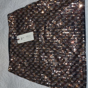 Glittrig paljettkjol, st S - Snygg glittrig kjol täckt med paljetter i olika färger. Perfekt för en festlig kväll. Kjolen har en rak passform och är knälång.