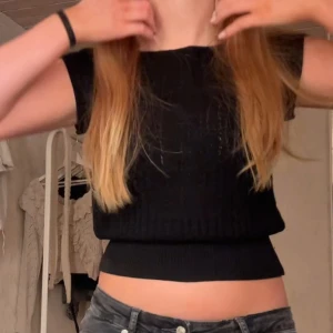 Svart ribbad topp - Snygg svart ribbad topp med korta ärmar. Perfekt för en stilren look. Passar bra till jeans eller kjol.