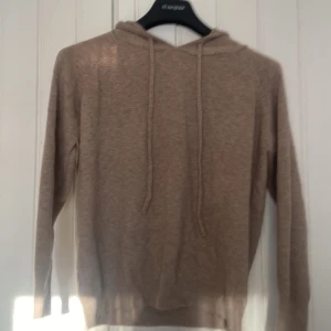 Kashmir hoodie - Säljer en stillren beige stickad hoodie i kashmir med långa ärmar och justerbar huva. Den har ribbade muddar vid ärmsluten för extra komfort. Säljer den pågrund av att den blev för liten för mig passar killar mellan 160-175cm