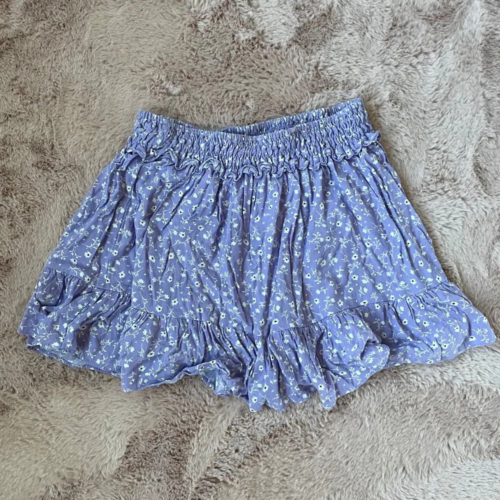 Säljer en söt kjol med blommigt mönster. Den har en elastisk midja och volangdetaljer som ger en romantisk touch. Perfekta för varma sommardagar!🎀💝. Hameet.