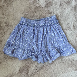 Mönstrad kjol - Säljer en söt kjol med blommigt mönster. Den har en elastisk midja och volangdetaljer som ger en romantisk touch. Perfekta för varma sommardagar!🎀💝