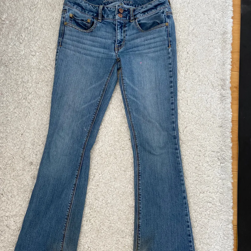 Snygga blå bootcut jeans med klassisk femficksdesign och knappgylf. Perfekta för en avslappnad stil. De har en lätt slitning vid fållen som ger en cool look. Innerbenslängden: 78.5cm och midjemått: 37cm. Farkut & Housut.