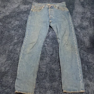 Levis 501 jeans - Klassiska Levis 501 jeans i ljusblå denim. Dessa jeans har en rak passform och är tillverkade av slitstarkt bomullsmaterial. Perfekta för en avslappnad stil med fem fickor och knappgylf.
