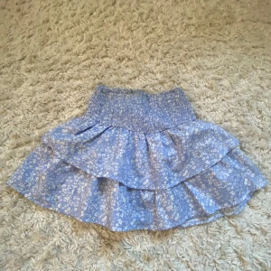 Blommig blå kjol från Gina Tricot - Söt blå volang kjol från Gina Tricot med ett blommigt mönster.🌸