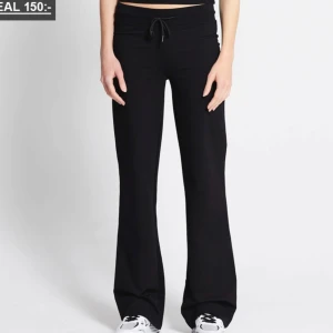 Svarta mjukisbyxor med bootcut och snörning - Svarta mjukisbyxor med bootcut och dragsko i midjan. Byxorna har en bekväm passform och är perfekta för en avslappnad stil. Tillverkade i mjukt material och har en lågmidjad design. Nyskick pga fel storlek