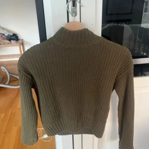 Olivgrön stickad tröja med polokrage - Säljer en olivgrön stickad tröja med polokrage. Tröjan har lång ärm och ribbade muddar vid ärmslut och nederkant. Perfekt för kyligare dagar och enkel att matcha med jeans eller kjol. Strl 34 från hm 