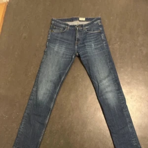 Blå jeans från Tiger of Sweden - Säljer ett par klassiska blå jeans från Tiger of Sweden. De har en smal passform, fem fickor och snygga slitningar på låren. Perfekta för dig som gillar stilrena och tidlösa jeans med modern känsla.