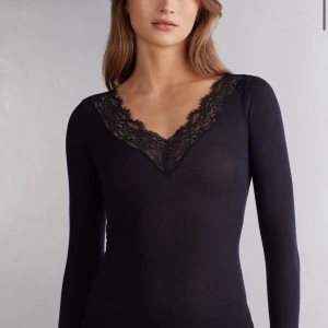 Svart långärmad topp med spetsdetaljer - Säljer en svart långärmad topp med v-ringning och fina spetsdetaljer både vid halsringningen och ärmsluten. Tunn och mjuk, perfekt att styla till olika outfits. Den är lite nopprig och har ett litet hål vid sidan av tröjan, men de är inget man lägger märket till!☺️vill ni se bilder på defekterna är de bara att skiva 🤗🙌🏼