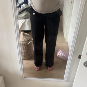 Svarta kostymbyxor med raka ben - Säljer ett par svarta kostymbyxor med medlehög midja och raka, vida ben. Byxorna har klassisk passform och är perfekta för en stilren look. Tillverkade i ett mjukt material som känns bekvämt hela dagen.