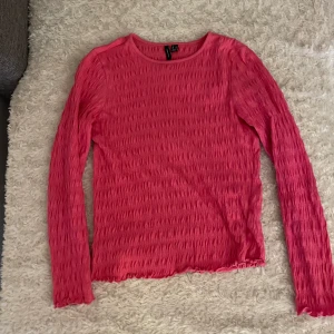 Rosa långärmad topp  - Säljer en rosa långärmad topp med strukturerat, vågigt tyg. Rund halsringning och figurnära passform. 