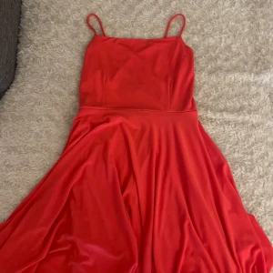 Rosa klänning med smala axelband - Säljer en rosa klänning med smala axelband och elegant, svepande kjol. Klänningen har en enkel och stilren design med öppen rygg och korsade band baktill. 