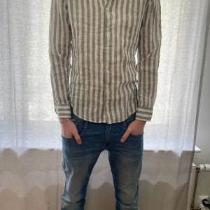 Randig linneskjorta från La Chemise Norrmalm - Säljer nu min pojkväns skjorta från La Chemise Norrmalm då den är för liten. Han är 195 cm och det är storlek 41 på skjortorna som motsvara ungefär storlek L.  Skjortan är i linne och har en slim passform med knappar framtill. Perfekt för en stilren look.