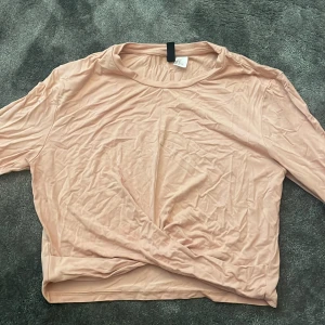 Ljusrosa långärmad topp - Säljer en enkel och stilren ljusrosa långärmad topp i mjukt material. Perfekt att matcha med jeans eller kjol för en avslappnad look. 