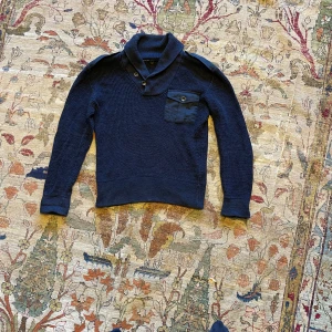 Sällsynt cardigan från Ralph Lauren - Black label ralph Lauren. Säljer en mörkblå stickad (linne) kofta från Ralph Lauren med snygg krage och knappar vid axel och hals. Tröjan har en bröstficka med knapp patches på armbågarna. 