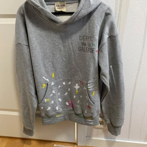 Gallery Dept Hoodie - Säljer en grå hoodie från Gallery Dept. med trycket 'DEPT. de la GALERIE' på bröstet. Hoodien har färgstänk i vitt, gult, rosa och grönt både fram och bak samt en stor magficka. Mjuk bomullskänsla och avslappnad passform. Storlek S baggy fit