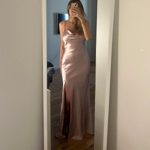 Ljusrosa långklänning i satin med slits - Säljer en elegant ljusrosa långklänning i satin med smala axelband och hög slits framtill. Klänningen har öppen rygg med figurnära passform. Säljer denna pga att jag hittat en annan klänning jag hellre vill ha. Aldrig använd endast testad och med alla lappar kvar!☺️ Nypris: 1399
