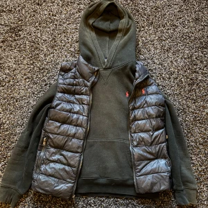 Ralph lauren väst och raplh lauren hoodie svart - Jag säljer 2 feta Ralph lauren plagg som man kan köpa tillsammans eller enskilt båda är i perfekt skick inga skador eller andra defekter. Båda=1200 kr väst ensam=750 hoodie ensam=550 de är bara att skriva om man vill köpa enskilt. De passar perfekt ihop och är självklart samma storlek. Storlek är Barn L eller ca 11-13 års ålder.PERFEKT TILL SOMMARN!