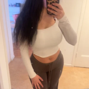 Vit croppad långärmad topp från Gina Tricot - Säljer en vit croppad topp från Gina Tricot i ribbat material. Toppen har långa ärmar och en tight passform som framhäver figuren. 