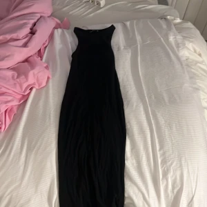 Svart långklänning från Zara - Säljer en svart långklänning från Zara. Klänningen är ärmlös och har en enkel, tight passform som framhäver siluetten. Perfekt för dig som gillar stilrena och minimalistiska plagg.