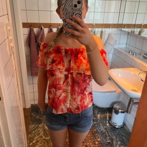 Blommig offshoulder-top från Bik Bok - Säljer en färgglad blommig offshoulder-top från Bik Bok i storlek S. Toppen har volang upptill och är i röda, orangea och vita nyanser. 