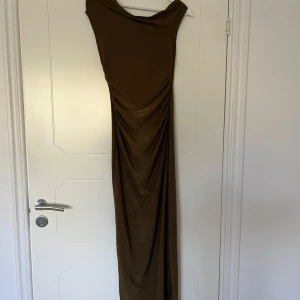 Satin klänning  - En maxi klänning i satin i en khaki färg. Vet tyvärr inte vart jag köpt den ifrån då alla lappar är klippta. Den är i strech och sitter väldigt fint mot kroppen och skulle passa flera strorlekar.