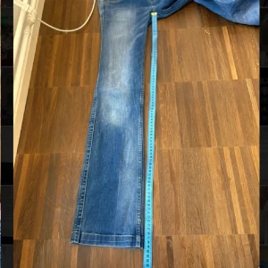 Blå Replay Jeans med bootcut - Säljer ett par klassiska blå jeans från Replay med bootcut och snygga slitningar. Jeansen har fem fickor, dragkedja och knapp framtill samt Replay-logga på bakfickan. Midjemått 36(se bild) inner lår 79( se bild)