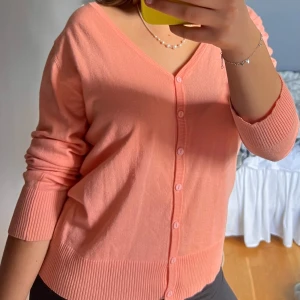 Persikofärgad kofta med v-ringning - Säljer en persikofärgad kofta med v-ringning och knappar framtill. 