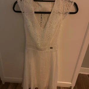 Vit spetsklänning från Chiara Forthi - Superfin vit klänning från Chiara Forthi med spetsdetaljer upptill och öppen rygg. Klänningen har kort längd, markerad midja och är ärmlös med vackra spetskanter. Perfekt för sommarens speciella tillfällen eller studenten☺️💕Ny pris 1000, den är tyvärr för liten därför jag säljer den. Använd endast en gång. 
