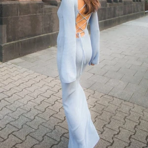 Ljusblå ribbad långklänning med öppen rygg och snörning - Supersnygg stickad ljusblå långklänning i ribbat material med lång ärm. Baksidan har en öppen rygg med snygg snörningsdetalj. Perfekt för dig som vill sticka ut med en trendig och bekväm look. Klänningen är från NA-KD och använts 1 gång. Nypris- 699kr✨