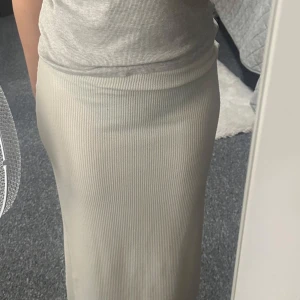 Vit ribbad långkjol från Boohoo - Säljer en vit ribbad långkjol från Boohoo. Kjolen har en fin passform och en liten slits baktill för extra rörelsefrihet. Perfekt att styla med en enkel topp till sommaren!