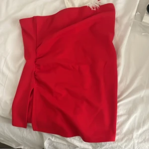 Röd topp  med slits - Snygg röd topp med en liten slits på sidan och lätt rynkdetalj. Toppen har en enkel, stilren design och är perfekt för dig som vill sticka ut. Passformen är normal och materialet känns mjukt och följsamt.