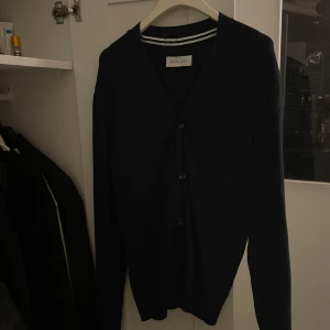 Mörkblå kofta från Pier One - Snygg mörkblå kofta från Pier One med v-ringning och knappar framtill. Långärmad och i mjukt material som passar perfekt till lager-på-lager. Enkel och stilren design som funkar till många outfits.