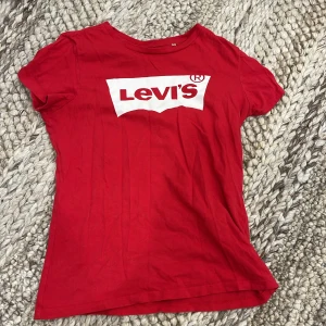 Röd Levi's t-shirt med logga - Röd t-shirt från Levi's i mjuk bomull med klassisk vit logga framtill. Modellen är kortärmad och har en rund halsringning. 