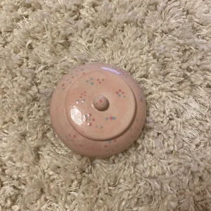 Keramisk sminkburk med lock - Söt rund sminkburk i ljusrosa keramik med lock. Prickigt mönster i blått och rosa både på utsidan och insidan. Perfekt att förvara sminkborstar, pads eller småsaker i på sminkbordet. Handgjord känsla och unik design.