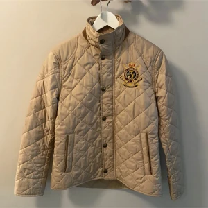 Beige quiltad jacka från Ralph Lauren - Säljer nu min beiga jacka från Ralph Lauren som är köpt i New York. Jackan är använd ett få tal gånger och har inga tecken på användning.