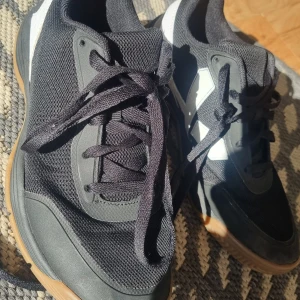 Svarta sneakers från SOC strl 38 - Svarta sneakers från SOC med vita detaljer och gummisula. Ovandelen är i mesh och syntet, vilket ger bra andningsförmåga. Skorna har snörning och en platt, greppvänlig sula som passar perfekt för träning inomhus eller gymmet.