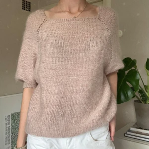 Ljusrosa stickad tröja med öppen rygg - Superfin ljusrosa stickad tröja med korta ärmar och en snygg öppen detalj i ryggen som stängs med en glittrig knapp. 