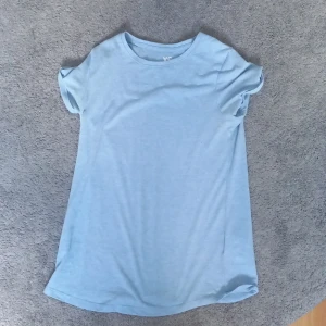 Ljusblå t-shirt från FSBN Sister XS - Enkel och stilren ljusblå t-shirt från FSBN Sister i storlek XS. T-shirten har rund halsringning och korta ärmar med lätt upprullad kant. Tillverkad i mjuk bomull för en skön känsla hela dagen.