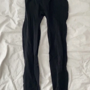 Svarta scrunch-leggings med hög midja - Svarta leggings med scrunch-detalj bak och bred, hög midja. Tight passform och stretchigt material som sitter snyggt och bekvämt. Perfekta för gymmet eller chill hemma.