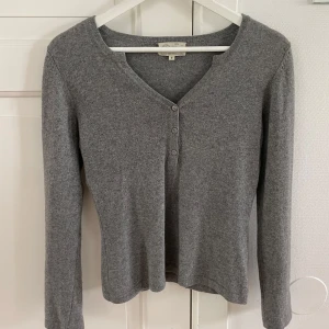 Grå kashmirtröja med knappar - Supermjuk grå tröja i 100% kashmir från CF Cashmere. Tröjan har v-ringning med tre knappar framtill och lång ärm🩶🩶